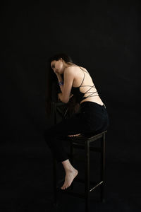 Low angle view of woman standing against black background