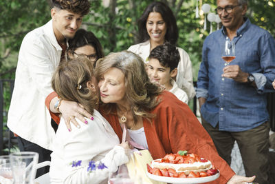 Women embracing each other near family during dinner party