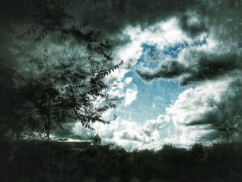 Trees against storm clouds in sky