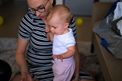 Rear view of mother carrying daughter at home