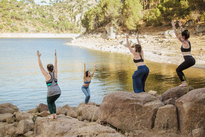 Rear view of people standing on rock by lake