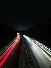Light trails on highway against sky at night
