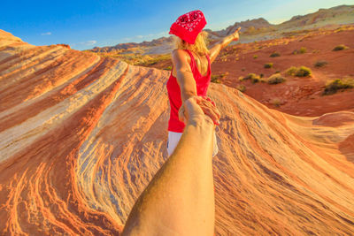 Cropped image of man holding mature woman hand on rock formation at desert