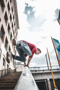 Low angle view of man standing by railing against sky