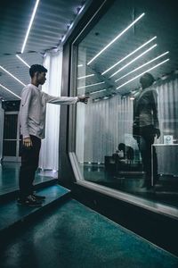 Rear view of man looking at illuminated room