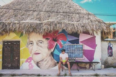 Young woman standing by tree against sky