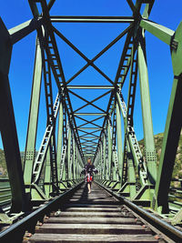 Rear view of woman on footbridge against sky