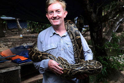 Man holding a 10kg constrictor snake. vietnamese tourist activity.