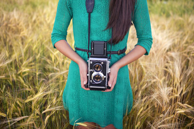 Midsection of woman photographing on field