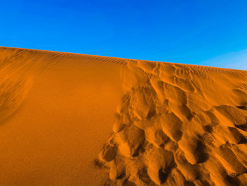 Scenic view of desert against clear blue sky