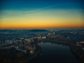 Aerial view of river flowing in town during sunset