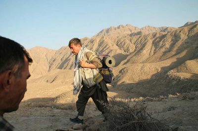 Men standing on rock in desert against sky