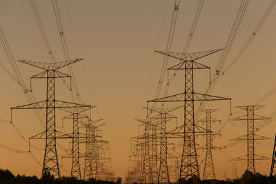 Low angle view of silhouette electricity pylon against sky during sunset