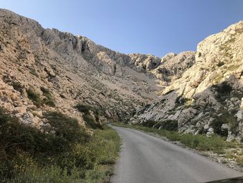 Road amidst mountains against clear sky