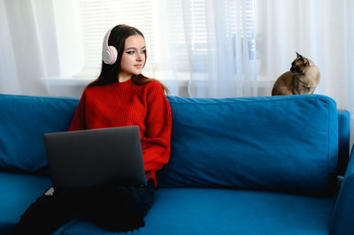 Young woman using laptop while sitting on sofa at home