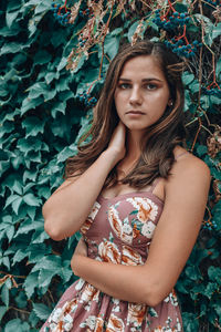 Portrait of young woman standing against plants