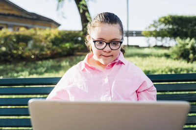 Teenage girl with down syndrome using laptop in park