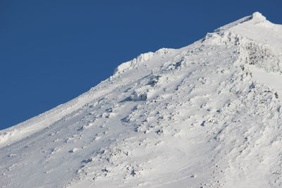 Snow covered mountain against blue sky