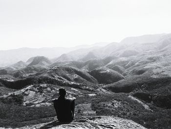 Rear view of woman standing on mountain against clear sky