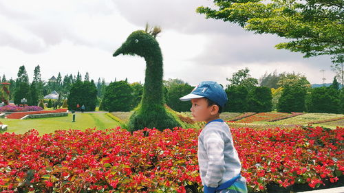 Side view of boy against bird topiary at botanical garden
