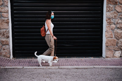 Full length of woman with dog against shutter