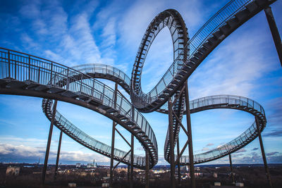 Low angle view of ferris wheel against cloudy sky