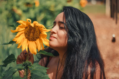 Close-up of beautiful woman with eyes closed smelling sunflower