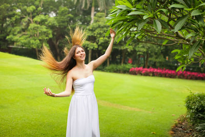 Happy young woman standing by plants