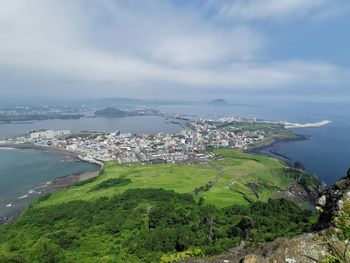 Aerial view of townscape by sea against sky