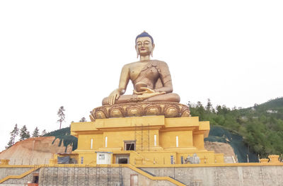 Low angle view of statue against temple against clear sky