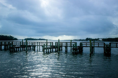 Pier in sea against cloudy sky