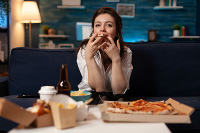 Portrait of woman eating pizza at home