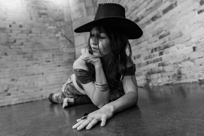 Full length of woman sitting against wall