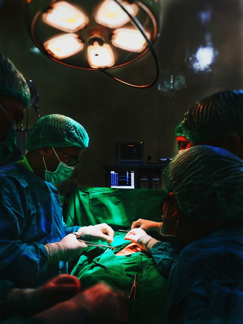 men, real people, indoors, people, group of people, illuminated, healthcare and medicine, adult, women, lighting equipment, doctor, green color, lifestyles, occupation, operating room, hospital, holding, males, leisure activity, surgeon, care