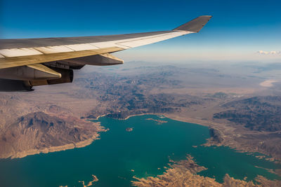 Cropped image of airplane flying over mountains against sky