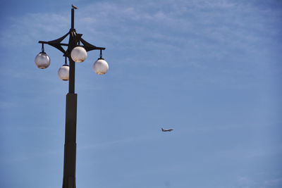 The lamppost looking at the plane in blue sky