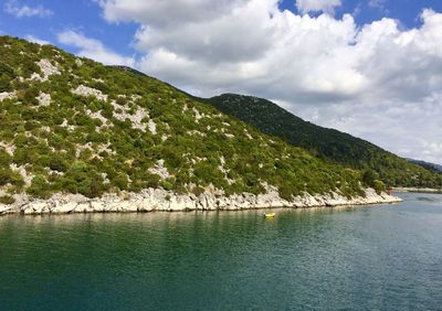 Scenic view of sea by mountains against sky