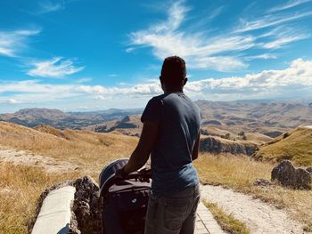 Rear view of man standing on mountain against sky