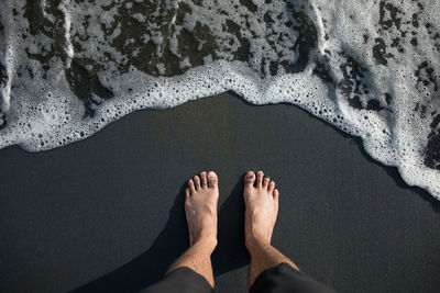 Low section of person standing at beach