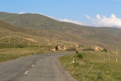 Road amidst field against sky