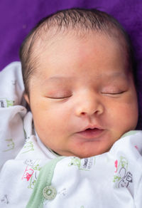 Newborn baby isolated sleeping in white cloth with purple background from different angle