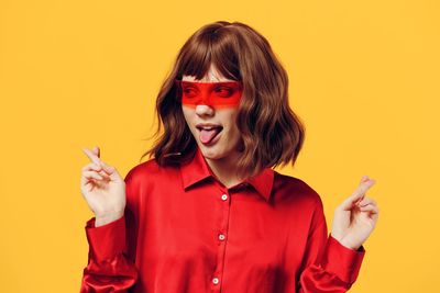 Portrait of young woman against yellow background