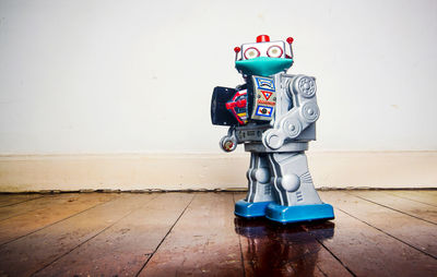 Close-up of toy on hardwood floor against blue wall