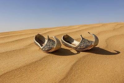 High angle view of shoes on sand at beach against sky