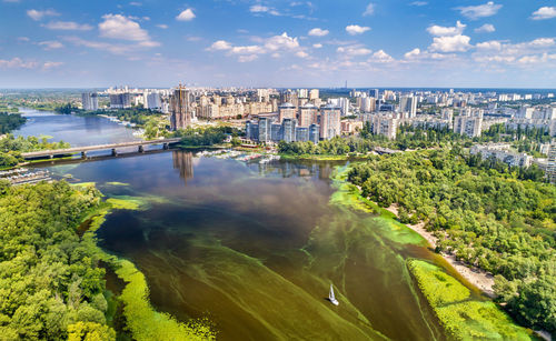 Aerial view of river amidst buildings in city against sky