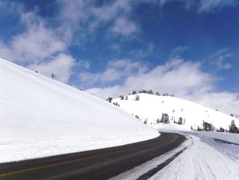 Road by snow covered mountain against sky