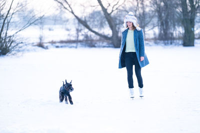Full length of person with dog on snow covered trees