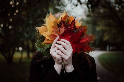 Close-up of woman covering face with leaves
