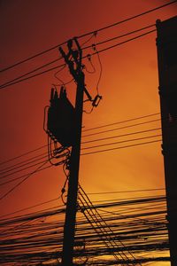 Low angle view of silhouette electricity pylon against sky during sunset