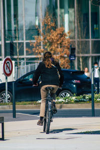 Rear view of woman riding bicycle on road